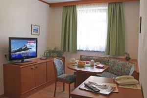 a living room with a television and a table and a couch at Hotel Bella in Obertauern