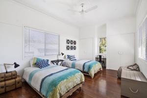 two beds in a room with white walls and wood floors at The Lighthouse in Toowoomba
