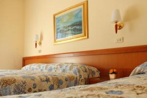 ミラノ・マリッティマにあるHotel Delle Nazioniのベッド2台が備わる客室で、壁には絵画が飾られています。