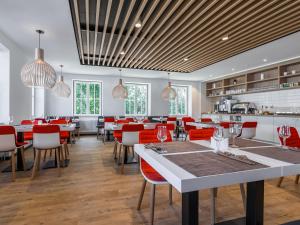 a restaurant with white tables and red chairs at Serways Hotel Siegburg West in Siegburg