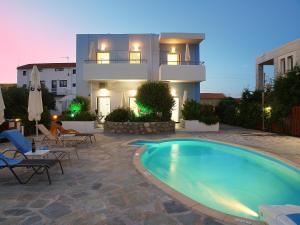 a villa with a swimming pool in front of a house at Almiris Seaside Apartments in Almirida