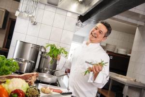 - un chef dans une cuisine tenant un paquet de légumes dans l'établissement Hotel Mediterraneo, à Neustadt an der Weinstraße