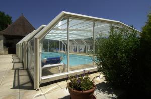 Una casa de cristal con piscina. en Hostellerie Clau del Loup - Logis Hotels, en Anglars-Juillac