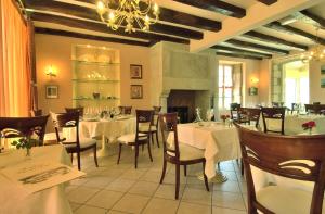 un restaurante con mesas y sillas blancas y una lámpara de araña en Hostellerie Clau del Loup - Logis Hotels, en Anglars-Juillac