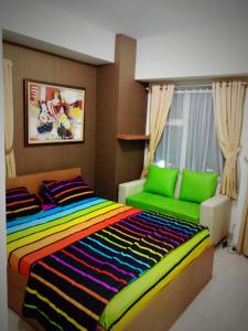 a bedroom with a colorful bed and a green couch at Wjy Apartment Margonda Residence 5 in Depok