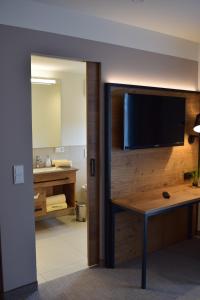 a bathroom with a tv and a table and a sink at Gasthaus Forster am See - Eching bei Landshut in Landshut