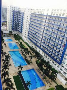 Sea Residences MOA-Eric Apartments في مانيلا: اطلالة جوية على مبنى كبير فيه نخيل ومسابح