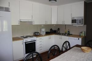 a kitchen with white cabinets and a stove and a table at Surkeenjärven Jaakon talot in Moksinkylä +13 photos