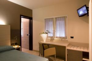 a bedroom with a desk and a window with a television at Locanda Benetti in Costabissara