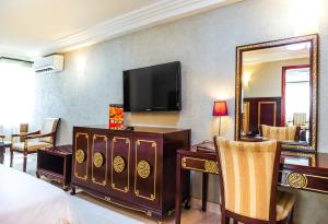 Habitación de hotel con cama y TV en la pared en Nobila Airport Hotel en Cotonú