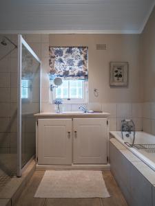 ein Bad mit einem Waschbecken, einer Badewanne und einem Fenster in der Unterkunft Franschhoek Rose Cottages in Franschhoek