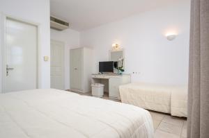 a white bedroom with two beds and a television at Astir Of Naxos in Naxos Chora