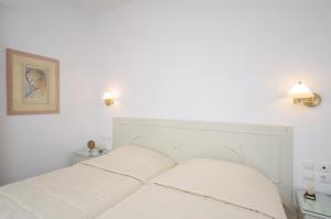 a white bed in a bedroom with two lamps at Astir Of Naxos in Naxos Chora