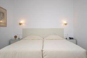 a white bed in a white bedroom with two lights at Astir Of Naxos in Naxos Chora