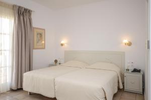 a bedroom with a large white bed and a window at Astir Of Naxos in Naxos Chora