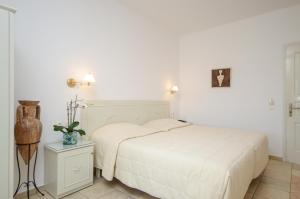 a white bedroom with a bed and a night stand at Astir Of Naxos in Naxos Chora