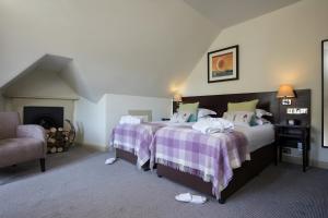 a bedroom with two beds and a fireplace at Nether Abbey Hotel in North Berwick