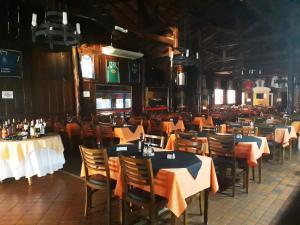 a dining room with tables and chairs with orange table cloth at Cristal Palace Inn in Lins