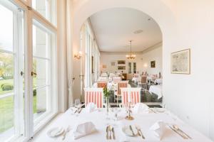 a restaurant with white tables and chairs and windows at Hotel Schloss Storkau in Storkau +124 photos