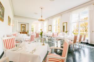 a restaurant with white tables and chairs and windows at Hotel Schloss Storkau in Storkau