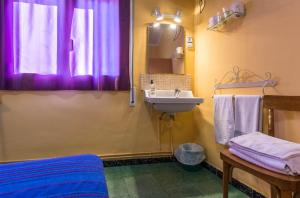 uma casa de banho com um lavatório e uma janela com cortinas roxas em Hostal Urgell em Balaguer