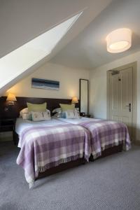 a bedroom with a large bed with a purple blanket at Nether Abbey Hotel in North Berwick