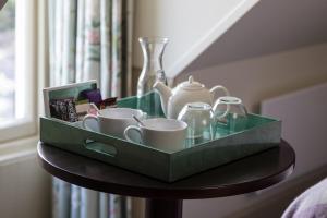 a table with a green tray with cups and tea cups at Nether Abbey Hotel in North Berwick