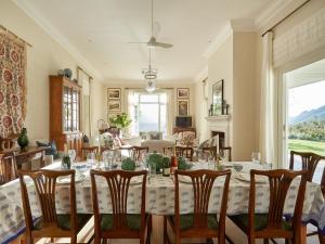 Un comedor con una mesa larga y sillas. en La Cotte House, en Franschhoek