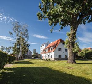 een groot wit huis met een boom in een veld bij Hotel Dorfmühle in Lehrberg
