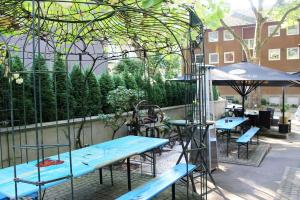 eine Terrasse mit blauen Tischen, Stühlen und einem Sonnenschirm in der Unterkunft Hotel Nüller Hof in Wuppertal