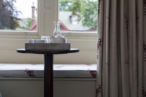 a table with a vase on it next to a window at Nether Abbey Hotel in North Berwick