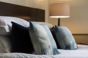 a bed with blue pillows and a lamp on it at Nether Abbey Hotel in North Berwick