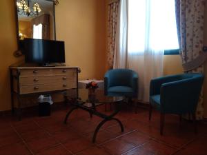 a living room with two chairs and a dresser and a television at Hotel Alonso de Monroy in Belvis de Monroy