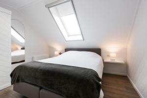 a bedroom with a large white bed with two windows at Chez Marly in Oosterblokker