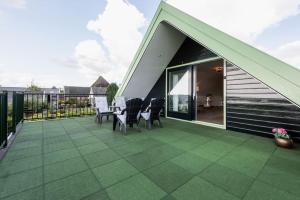 a roof deck with chairs and tables on a house at Chez Marly in Oosterblokker
