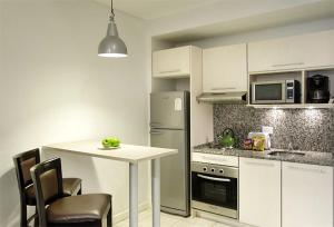 Una cocina con gabinetes blancos y una mesa con sillas. en Piccaluga Apartments, en Buenos Aires