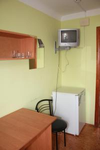 a kitchen with a refrigerator and a table and a tv on the wall at Vydubychi in Kyiv