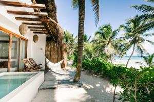 a villa with a hammock on the beach at The Beach Tulum Hotel in Tulum