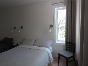 a bedroom with a bed and a chair and a window at Auberge Île du Repos in Honfleur