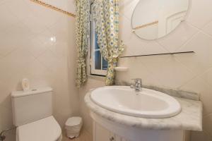 a bathroom with a sink and a toilet and a mirror at Villa - Duna Parque Group in Vila Nova de Milfontes