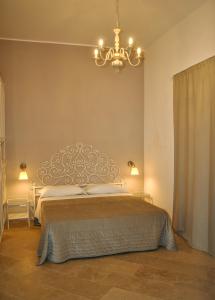 - une chambre avec un grand lit et un lustre dans l'établissement Case Gallina, à Avola