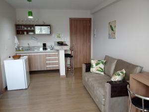 a living room with a couch and a kitchen at Pedra Azul - Flat Particular in Pedra Azul