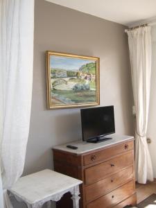 a bedroom with a dresser with a tv and a painting on the wall at AU VALLON ROUGE (Studio) in Saint Paul de Vence