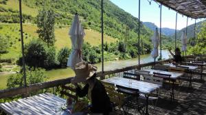 a woman sitting at a table with an umbrella at Hôtel-Restaurant Le Parisien in Les Vignes