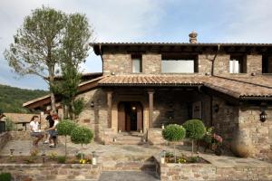 two people sitting in front of a stone house at El Acebo de Casa Muria in Bisaurri