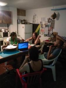 eine Gruppe von Menschen, die um einen Tisch mit einem Laptop sitzen in der Unterkunft La Choza Guesthouse in Santo Domingo