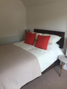 - une chambre avec un lit et 2 oreillers rouges dans l'établissement The Copper Coin, à Winford