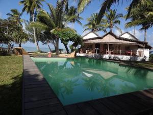 - une piscine en face d'une maison avec des palmiers dans l'établissement Hotel Club Paradise, sur l'île Sainte-Marie