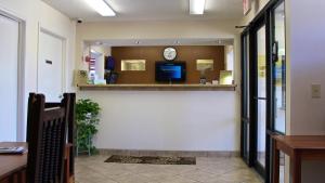 una sala de espera con un reloj en la pared en Carom Inn a Travelodge by Wyndham Denham Springs-Baton Rouge en Denham Springs