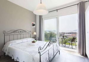 a white bedroom with a bed and a large window at B&B Stella Maggiore in Verbania